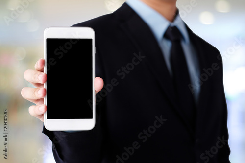 Businessman hand holding smartphone with blank on screen display over blur background, business people and technology display montage, mock up, template, background