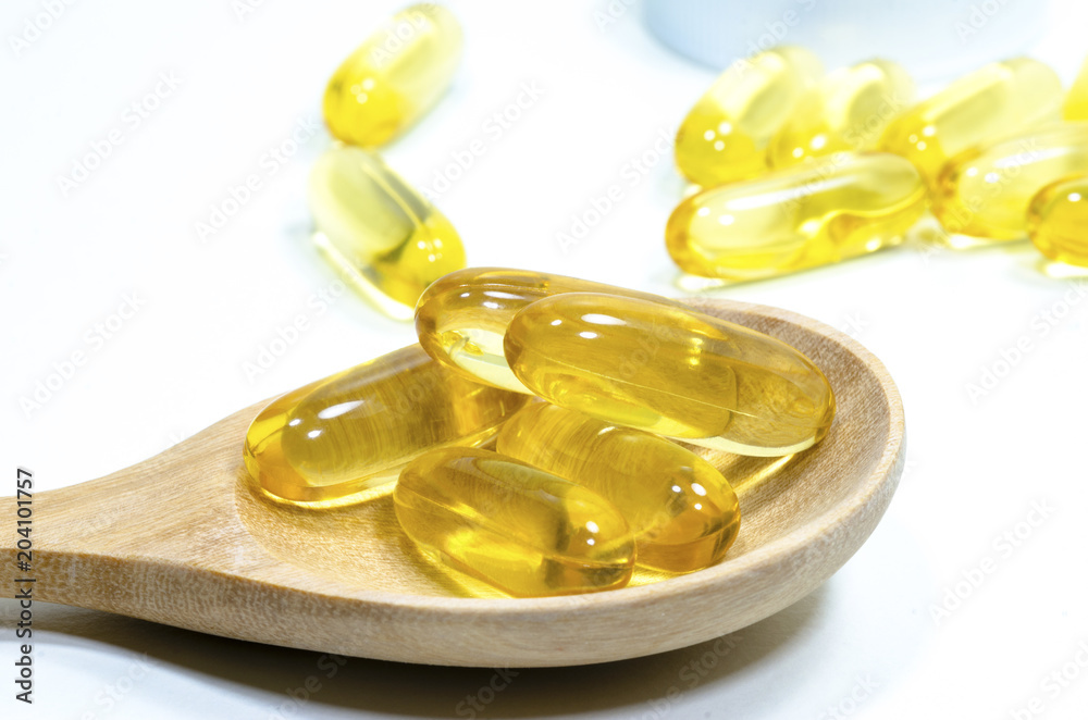 Fish liver oil in a wooden spoon against a white background. Fish liver oil in a wooden spoon against a white background.