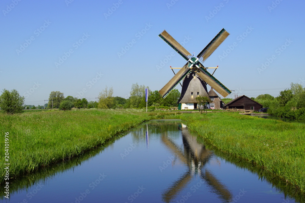 Typical Dutch traditional wooden windmill reflecting in the water.