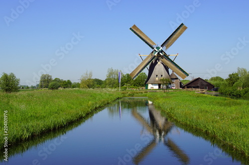 Typical Dutch traditional wooden windmill reflecting in the water.