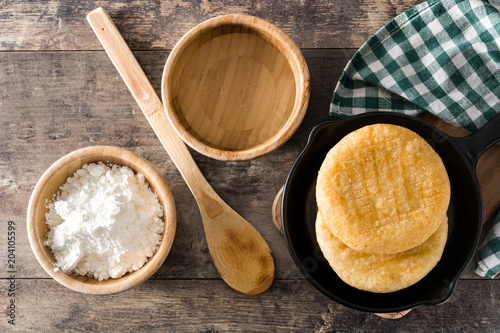 Arepas in iron pan on wooden table. Venezuelan typical food. Top view