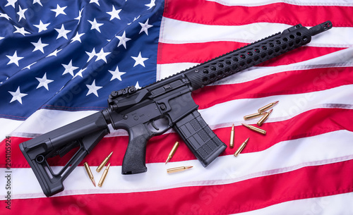 Custom built AR-15 carbine and bullets on American flag surface, background. Studio shot.