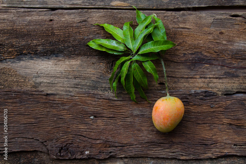Fototapeta Naklejka Na Ścianę i Meble -  Mango fruit with leaf on wooden background, top view