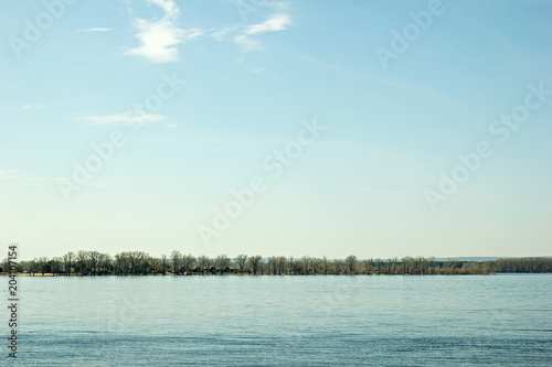 View of the right bank of the Volga River - trees and summer houses opposite the embankment of Samara city during the spring flood