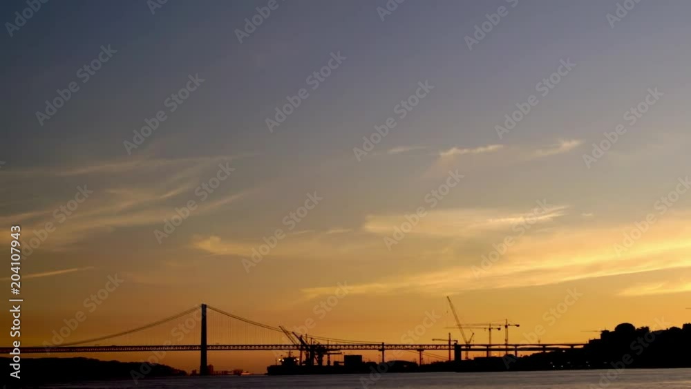 Panoramic view of Ponte 25 de Abril bridge and Tejo River in Lisbon, Portugal during a beautiful sunset Panoramic view of Ponte 25 de Abril bridge and Tejo River in Lisbon, Portugal during a beautiful sunset