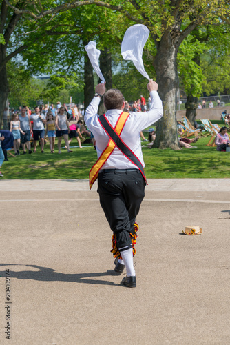 isolated single morris dancer with red an yellow sash waves two hankerchiefs in the air photo