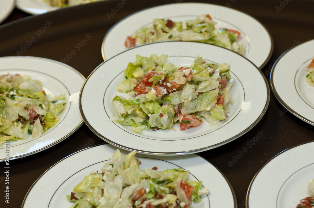 Fresh green salad with feta cheese and tomatoes on party plates Fresh green salad with feta cheese and tomatoes on party plates