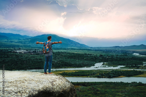 Hipster man with backpack enjoying sunset on peak of foggy mountain. Tourist traveler on background view mockup. Hiker looking sunlight in trip in Spain country, mock up text.