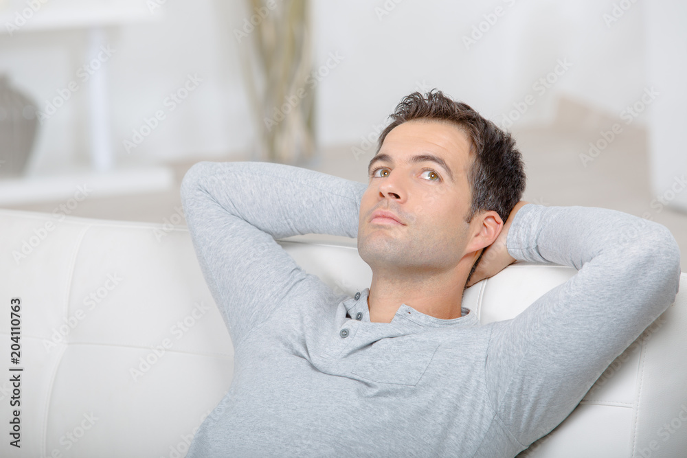 happy young man relaxing in sofa with arms behind head