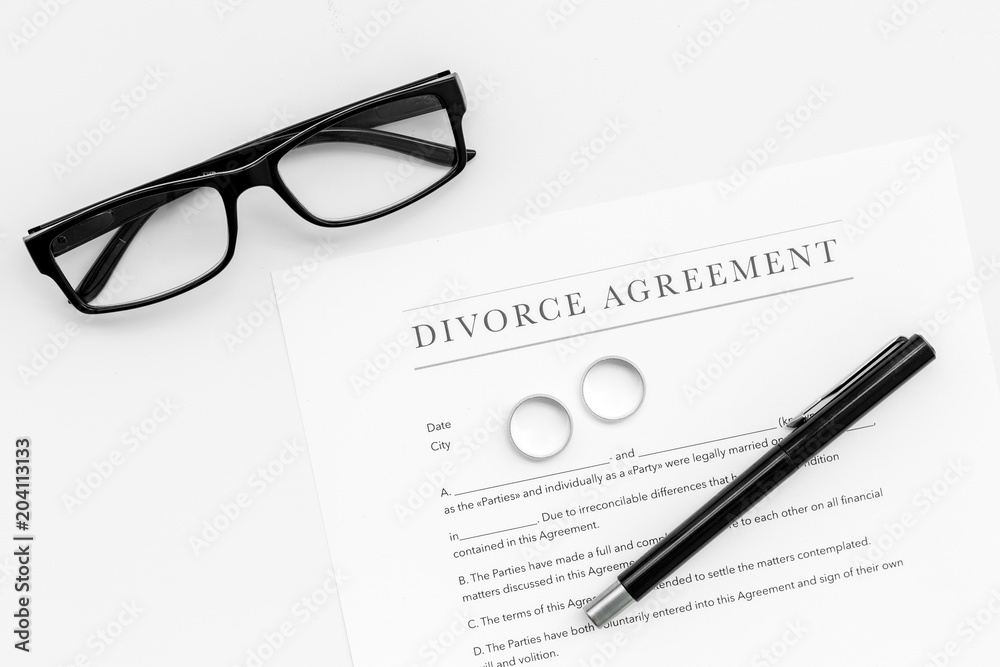 Divorce agreement. Wedding ring on document on white background top view copy space Divorce agreement. Wedding ring on document on white background top view copy space