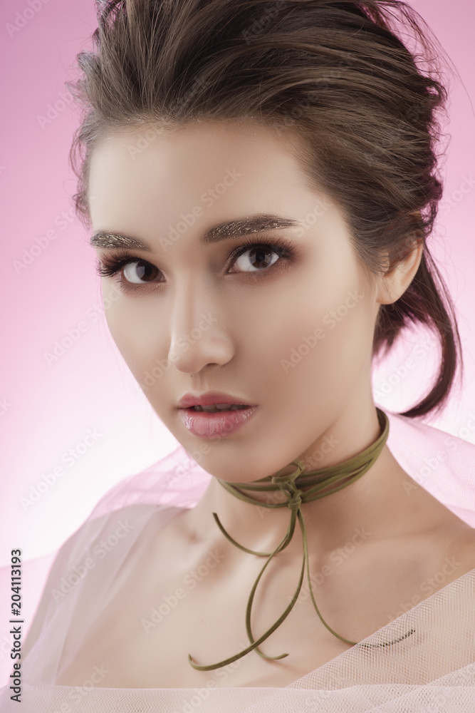 Fototapeta premium Closeup portrait of a beautiful young asian girl wearing pink veil on her naked shoulders and a choker on her neck.