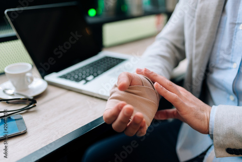 Photography Men with injured bandaged hand sitting at the table in the cafe
