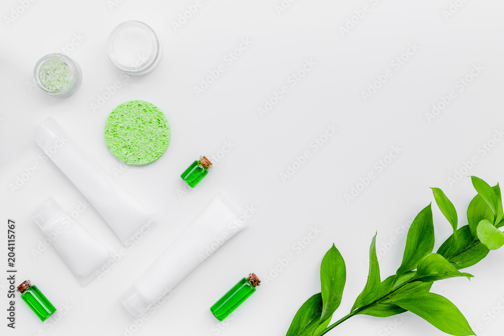 Organic skin care products. Cream, lotion, tonic. oil near green leaves on white background top view pattern Organic skin care products. Cream, lotion, tonic. oil near green leaves on white background top view pattern