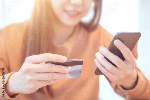 Woman hands holding credit card while using mobile smartphone. Online shopping concept.