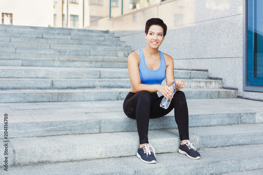 Fototapeta premium Woman runner is having break, drinking water
