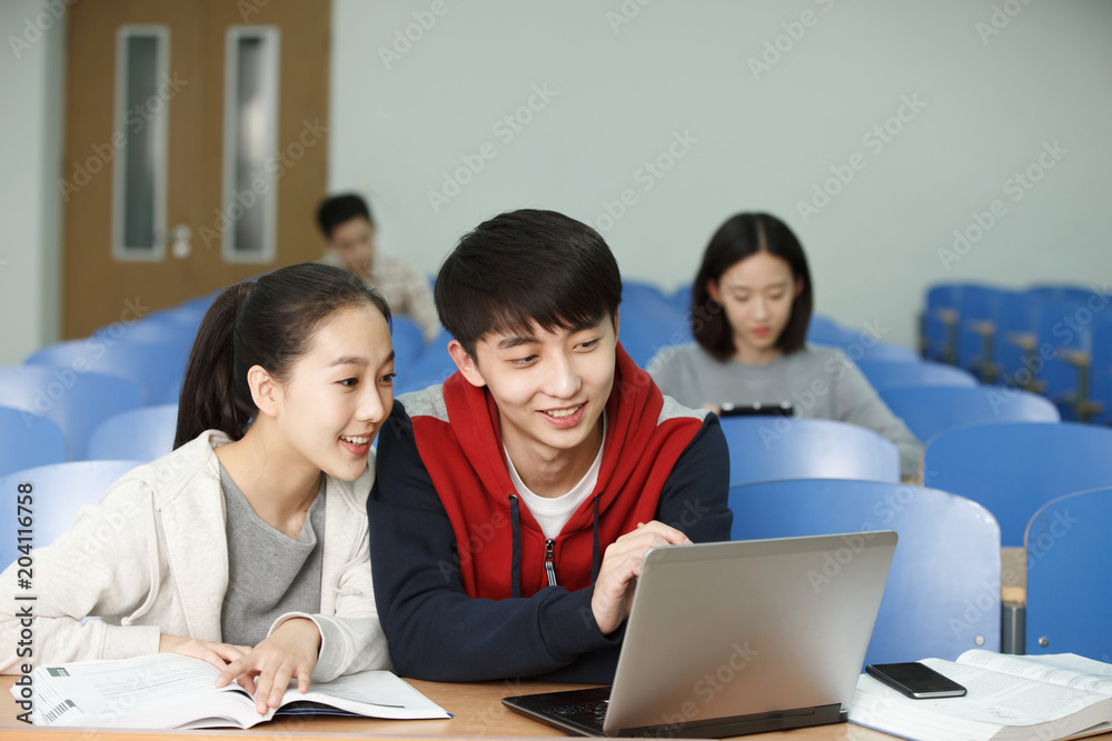 Student using a laptop while sitting in a classroom Student using a laptop while sitting in a classroom