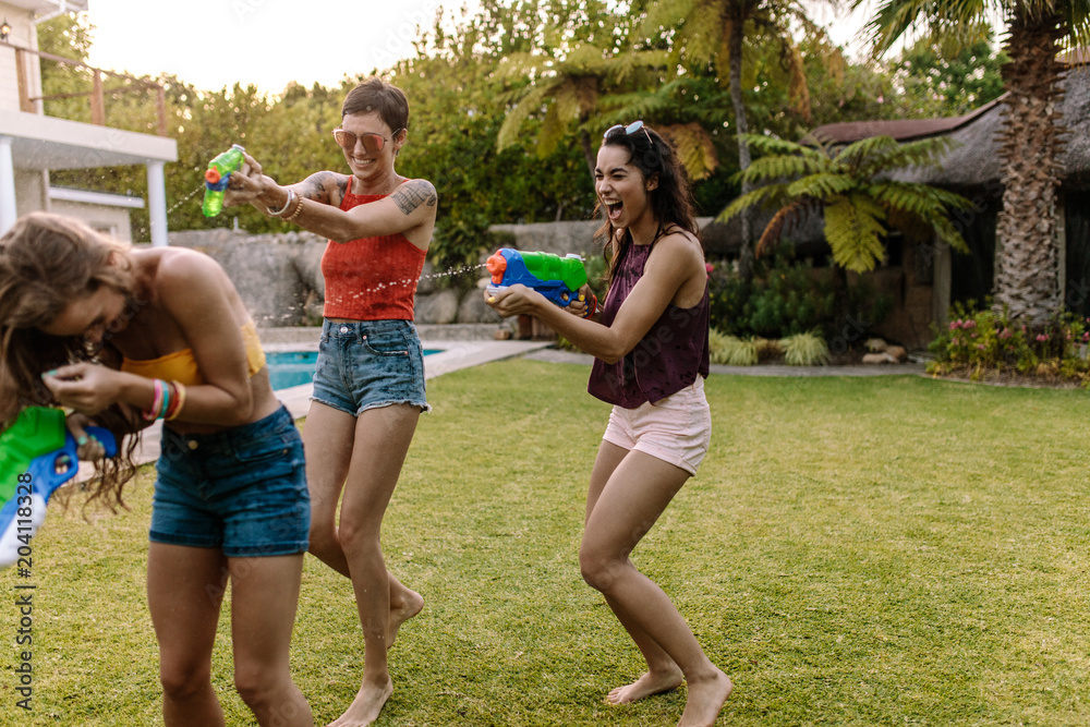 Fototapeta premium Friends having fun playing with water guns