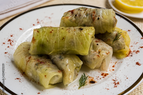 Delicious homemade stuffed cabbage leaves (the traditional dolma of the mediterranean cuisine) with red pepper in white plate