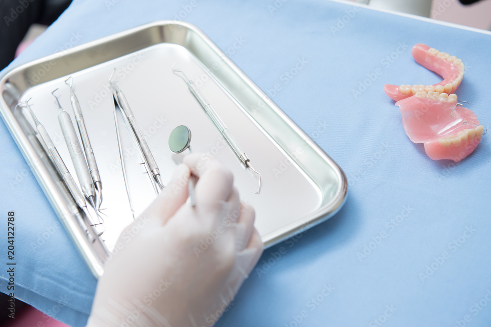 Metallic dentist tools close on and blue table sheet in a dentist clinic. with dentist hand Metallic dentist tools close on and blue table sheet in a dentist clinic. with dentist hand