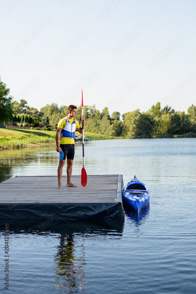 Young Professional Kayaker Getting Ready for Morning Kayak Training on River. Sport and Active Lifestyle Concept Young Professional Kayaker Getting Ready for Morning Kayak Training on River. Sport and Active Lifestyle Concept