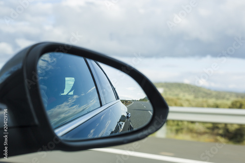 car on the road with motion blur background and rear view mirror. Travel concept. Cloudy sky
