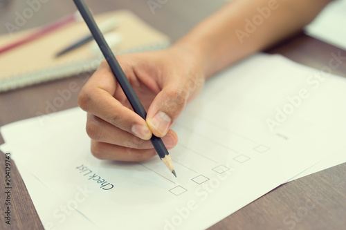 close up employee man hand using black pencil for checking list of inventory at office desk concept