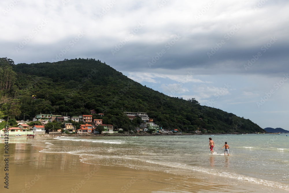 Florianopolis, Santa Catarina, Brazil. Tourists having fun on the beach while a storm cloud   is coming. 