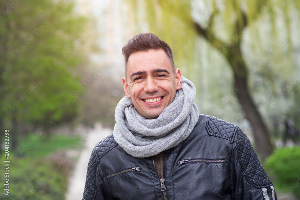 Portrait of a happy young man against a background of a city park. Smiling face. Portrait of a happy young man against a background of a city park. Smiling face.