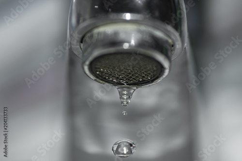 close-up of water drop falling from the silver tap