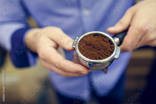 Imageof barista man with ground coffee in hands