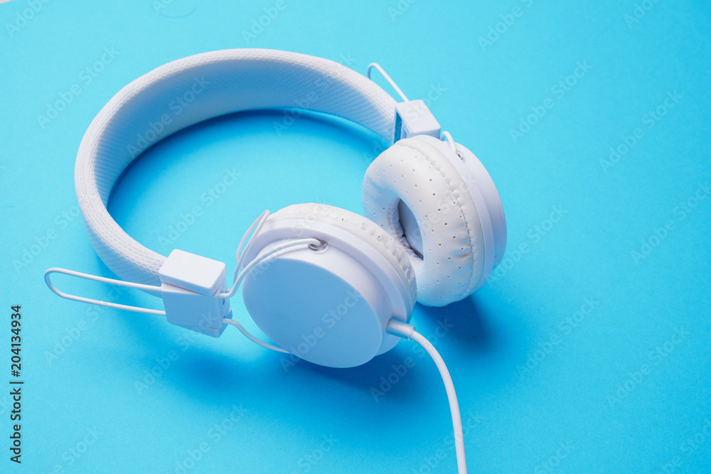 Photo of white headphones on blue background Photo of white headphones on blue background