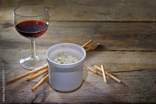 Photography potted blue stilton cheese in a ceramic jar, port wine and some nibble sticks on