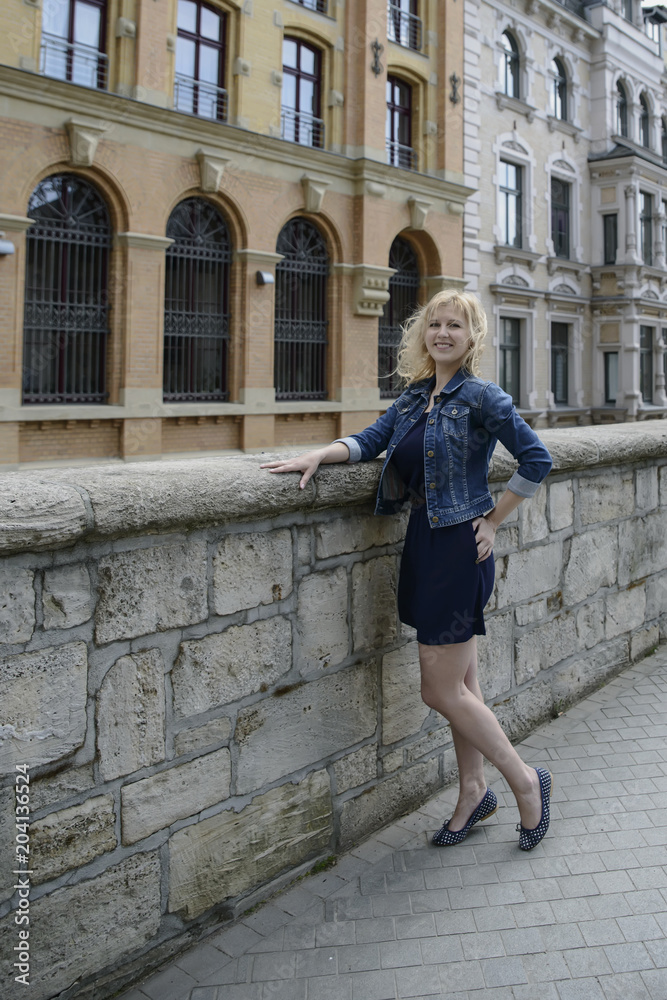 Young beautiful blonde model girl in the old town in the spring.
