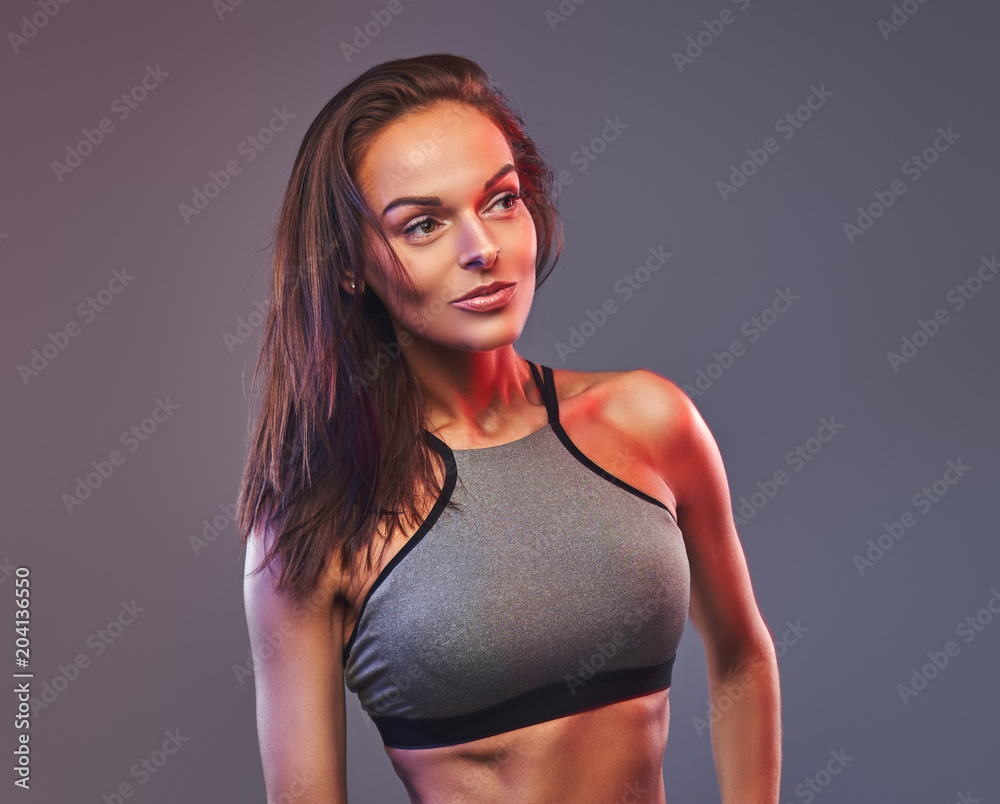 Slim fitness brunette woman in a gray sportswear posing in a studio. Slim fitness brunette woman in a gray sportswear posing in a studio.