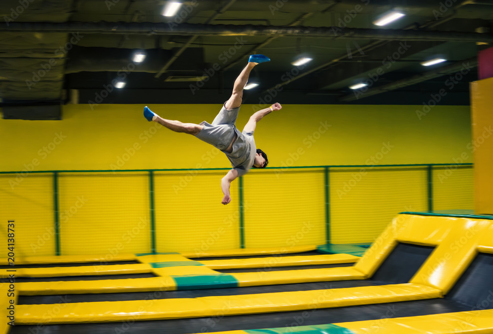 trampoline jumper performs complex acrobatic exercises and somersault on  the trampoline. Photos | Adobe Stock