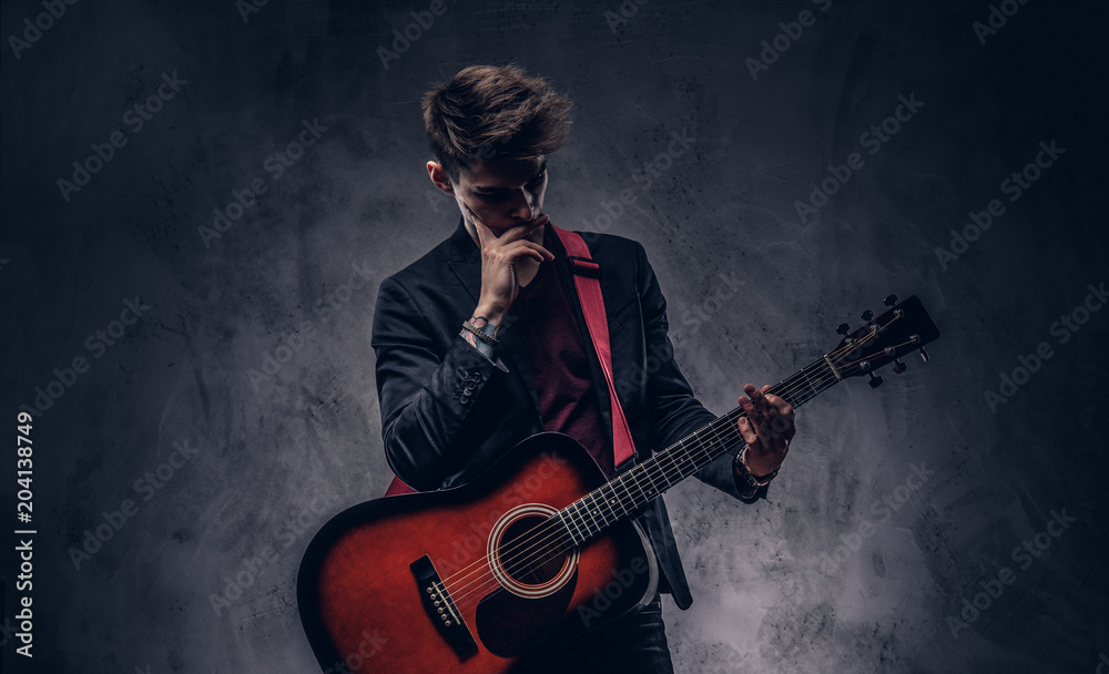 Fifteen Years Old Guitarist With A Black Electric Guitar. Teenage Musician  Holds Guitar, Posing At Studio. The Young Caucasian Guy With A Guitar.  Stylish Musician. Heavy Metal Player. Stock Photo, Picture and