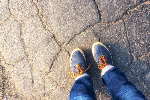 Women's feet in sneakers on the cracked asphalt.