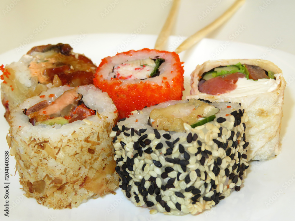 Sushi roll set with chopsticks served on white plate. Traditional japanese food Sushi roll set with chopsticks served on white plate. Traditional japanese food