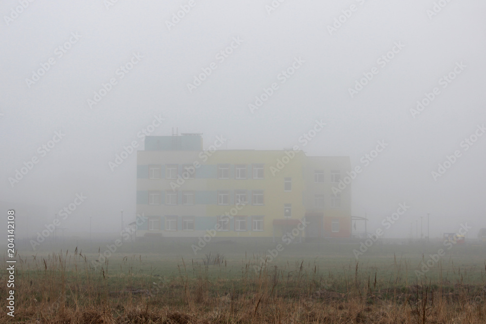 a lonely house in the fog in a vacant lot in the spring early in the morning. a lonely house in the fog in a vacant lot in the spring early in the morning.