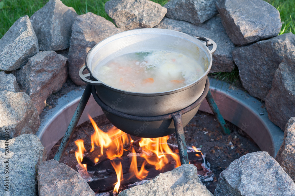 A cauldron with soup, which is cooked on a fire A cauldron with soup, which is cooked on a fire