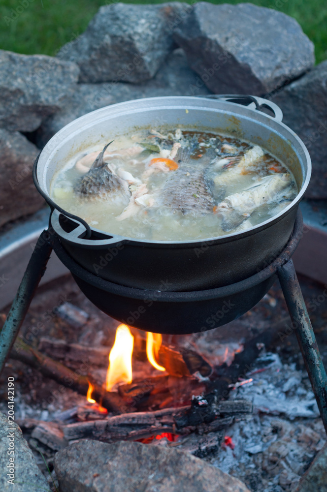 A cauldron with soup, which is cooked on a fire A cauldron with soup, which is cooked on a fire