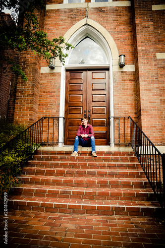 Teenager sitting on steps in front of church
