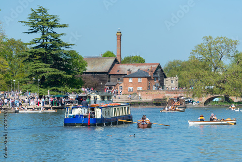 Photos large trip boat passes upstream on river amongst flotilla of smaller boats with