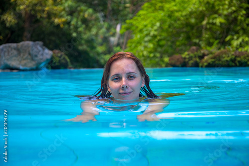 Relaxed woman in open swimming pool. Swimming girl looking in camera. Girl in open swimming pool.