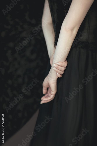 woman in black dress holding her hands at her back, sensual studio shot, can be used as background