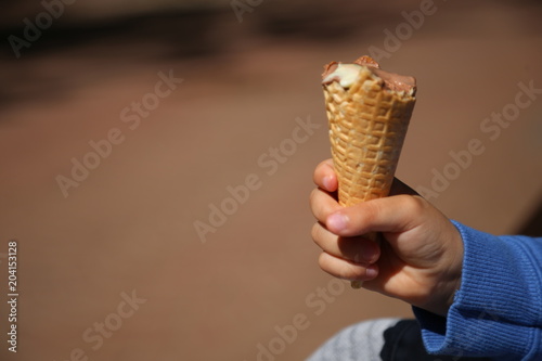 waffle ice cream in a child's hand close-up. the child takes a bite of ice cream