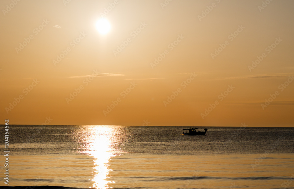 golden hour on the beach with a boat against the light