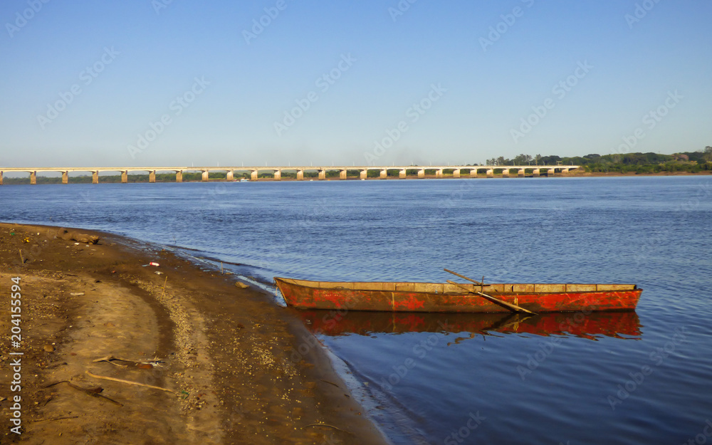 Canoe in the Uruguay river, International bridge on the border between Brazil and Argentina in the background (Uruguaiana, Brazil)