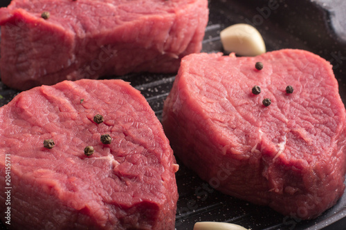 Raw beef meat with rosemary and garlic on a grill pan. Macro
