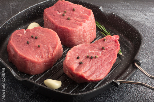 Raw beef meat with rosemary and garlic on a grill pan